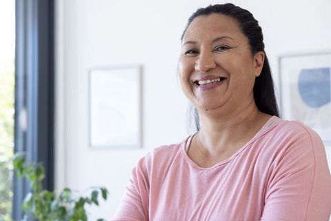 Confident african american woman smiling and standing in bright modern home interior