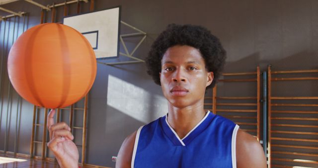 Young man displaying basketball skills in gym. Useful for adverts related to sports training, teamwork, athletic activities, motivational campaigns, fitness programs, and youth empowerment.