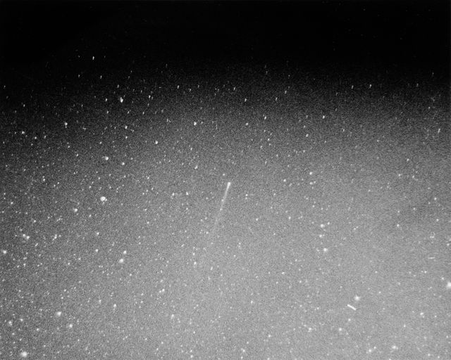 Photo shows Comet Kohoutek in night sky over Haleakala, Hawaii on Dec. 6, 1973. Captured by Frank Giovane using a Nikon camera with a 55mm lens and a 300-second exposure, it highlights comet's long tail amidst starry background. Useful for articles or presentations on comet observations, space phenomena, astronomy studies, and the history of notable celestial events.