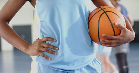Female Athlete Holding Basketball on Indoor Court