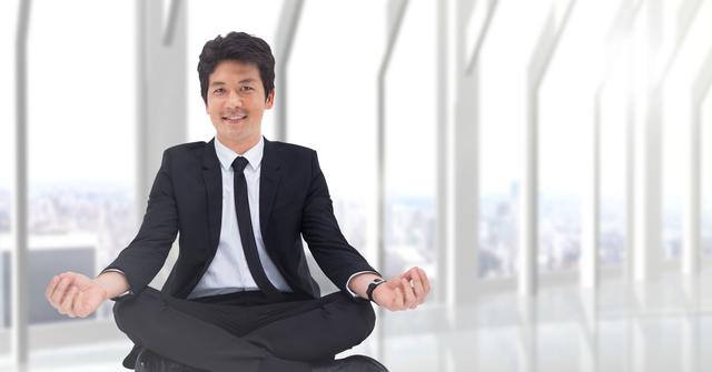 Businessman practicing meditation in modern office, representing corporate wellness and stress relief. Useful for illustrating corporate culture, professional mental health, work-life balance, and relaxation techniques.