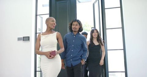 African american friends entering contemporary home dressed in elegant eveningwear