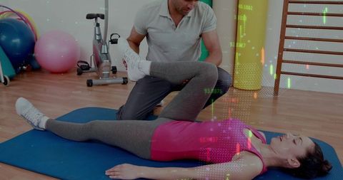 Kneeling trainer guiding client through assisted hip stretch on blue mat with data overlay