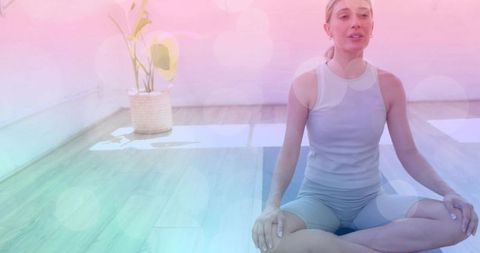 Calm woman practicing yoga on mat in bright studio wearing gray athletic set for wellness
