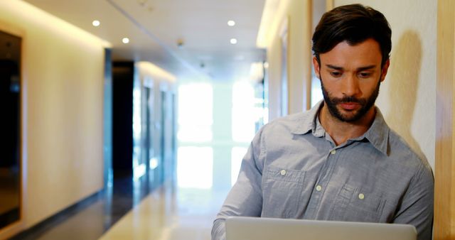 Serious Businessman Working on Laptop in Modern Office Hallway - Download Free Stock Images Pikwizard.com