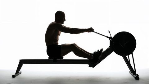 Silhouette male rowing on indoor rower high-contrast minimalist fitness training