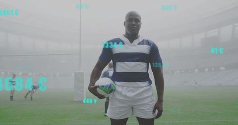 Rugby player standing on misty stadium pitch holding ball with teal data overlays