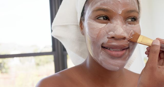 Smiling Woman Applying Face Mask with Brush in Natural Light - Download Free Stock Images Pikwizard.com