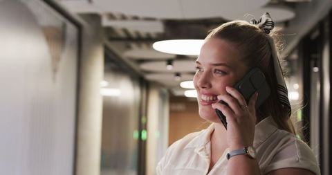 Businesswoman Conversing on Smartphone in Modern Corridor