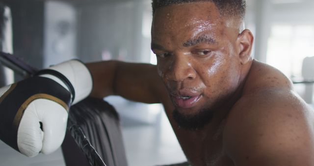 Image of fit and tired african american man resting after box training at gym. active, fit, sporty and healthy lifestyle, exercising at gym concept.