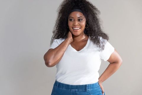 Confident african american woman smiling in white v-neck tee and blue jeans portrait
