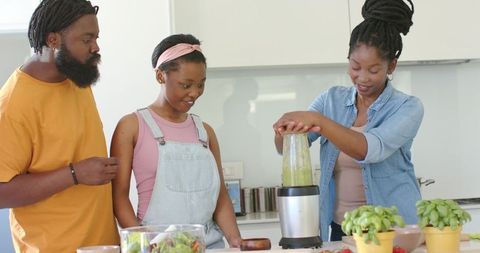Blending green smoothie together in bright kitchen family cooking and bonding