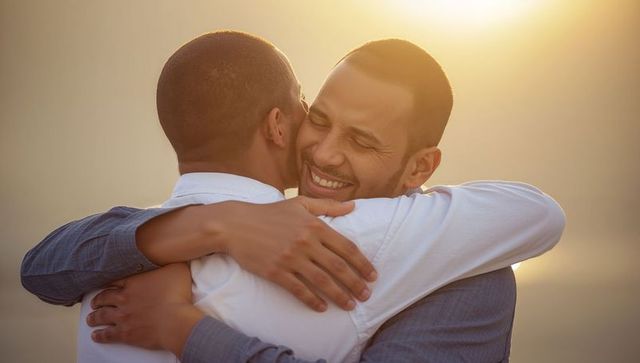 Two men hugging at sunset embracing friendship, warmth and brotherhood bond