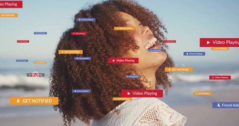 Laughing woman enjoying social media notifications on sunlit beach with play badges