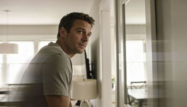 Man turning and looking back in home doorway with soft daylight and reflection