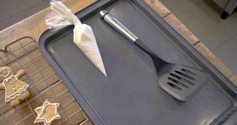 Baking tools with iced gingerbread cookies on rustic wooden countertop for holiday decor