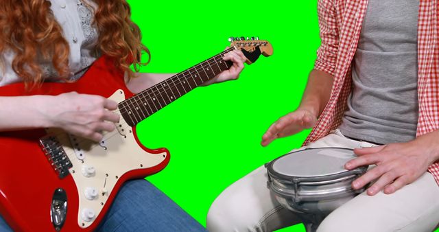Mid section of musicians playing guitar and drum against green background