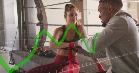 Boxing coach wrapping hands of female athlete in ring with green analytics overlay