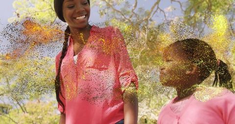 Sunlit bonding: woman and girl smiling in park with golden glitter light overlay