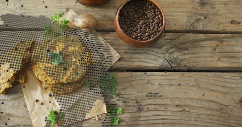 Golden crumbly veggie patties stacked on parchment with herbs and pepper on rustic wood