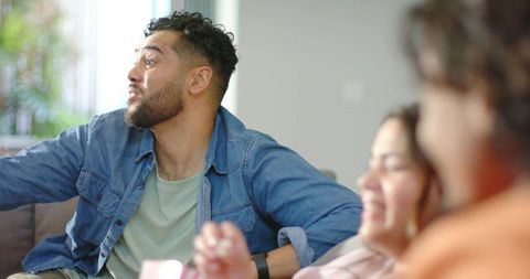 Diverse friends laughing and chatting on couch during bright casual living room moment