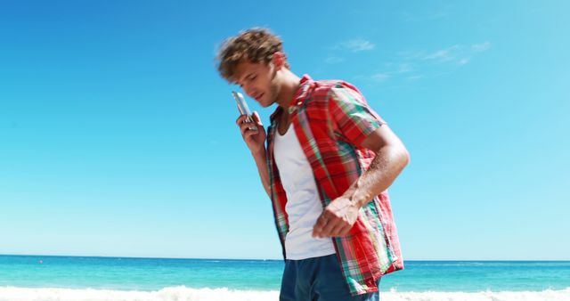 Young Man with Curly Hair Talking on Phone at Sunny Beach - Download Free Stock Images Pikwizard.com