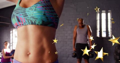 Cropped fitness torso raising arms showing toned abs while gym partner lifting kettlebells