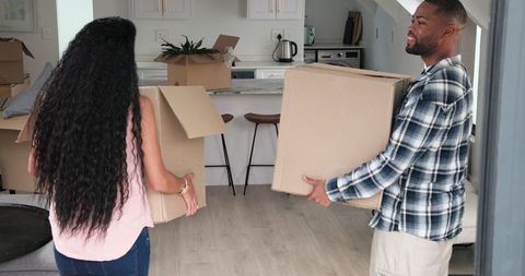 Couple Moving into New Home Carrying Boxes Together