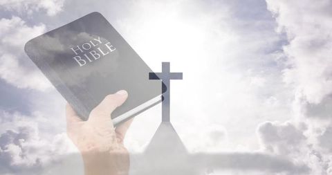 Hand holding holy bible against cloudy sky with silhouetted church cross, double exposure