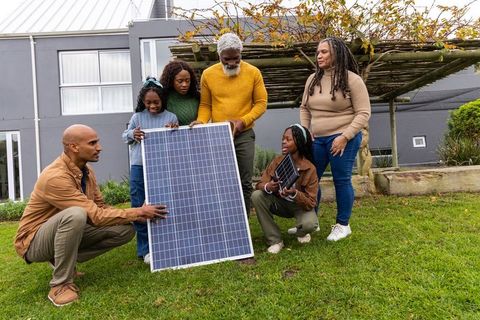 African american family installing solar panel in front yard demonstrating home solar