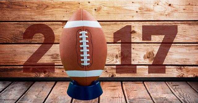 Digital composition of 2017 new year message with football against wooden background