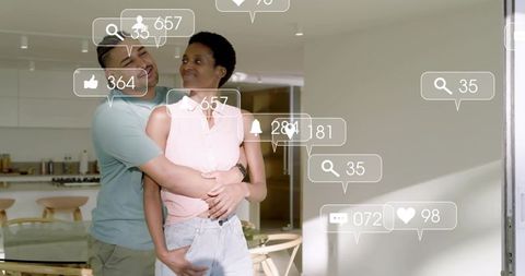 Couple embracing in modern kitchen with floating social media notifications, lifestyle