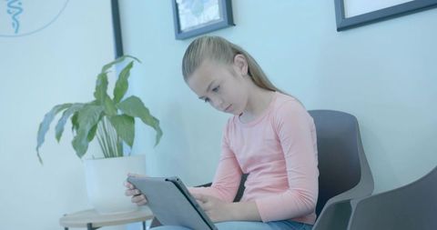 Young girl using tablet in bright reception area, learning on device, modern interior