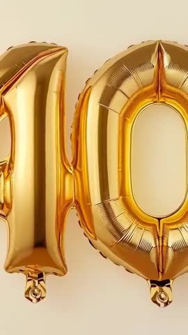 Vertical panning shot of gold 40 foil balloons gleaming on beige backdrop for milestone celebration