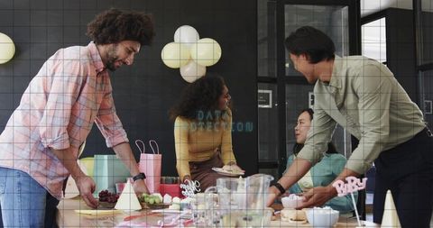 Office team celebrating with cupcakes and gifts around meeting table in modern workspace