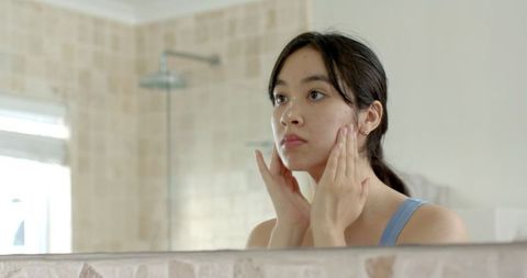 Woman Practicing Daily Skincare Routine in Modern Bathroom