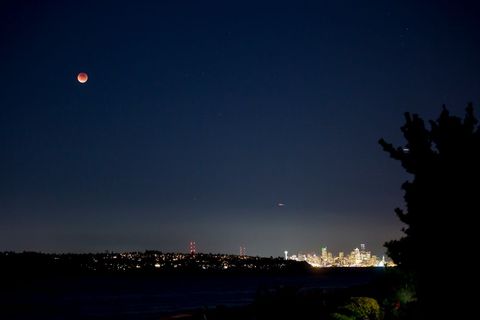 Lunar Eclipse Above Cityscape During Clear Night Sky