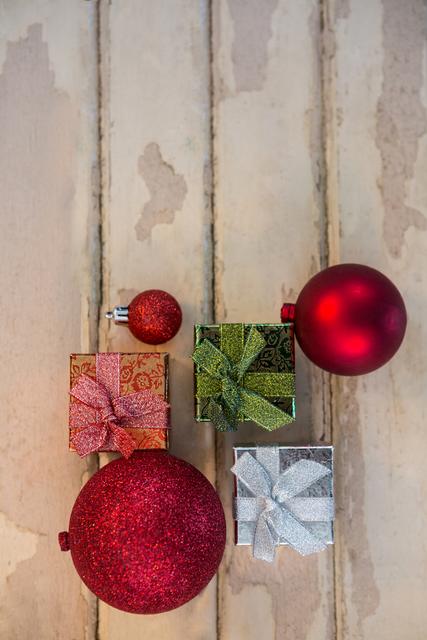 Bright and festive arrangement of gift boxes and baubles on rustic wooden plank. Ideal for holiday-themed advertisements, greeting cards, banners, and social media posts. Enhances content related to Christmas celebrations, gift-giving, and decorating ideas.