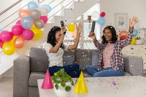 Joyful friends celebrating with confetti inside decorated home