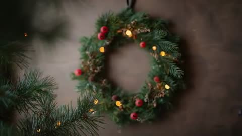 Pulling focus revealing rustic Christmas wreath with glowing lights and pine branch