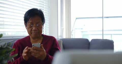 Senior Woman Engaged with Smartphone in Home Living Room