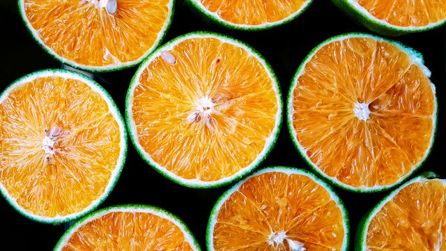 Top view of freshly sliced oranges with green peels, vibrantly showcasing their bright orange interiors. Perfect for use in culinary blogs, healthy eating promotions, juice advertisement, diet articles, and food-related publications.