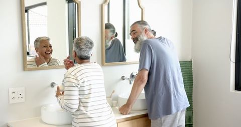Senior Couple Brushing Teeth in Modern Bathroom Mirror Reflection
