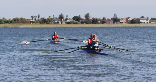 Photo depicts two rowing teams practicing on a calm lake on a sunny day. The teams are rowing in synchronicity, indicating coordination and teamwork. The lake is surrounded by houses and greenery, suggesting a serene residential area ideal for outdoor activities. Perfect for illustrating concepts related to sports training, fitness, team dynamics, and recreational activities.