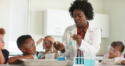 Female science instructor demonstrating chemistry experiment to elementary students