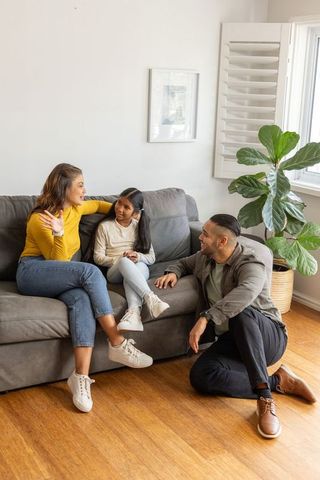 Modern family talking with daughter on gray sofa in bright living room casual parenting moment
