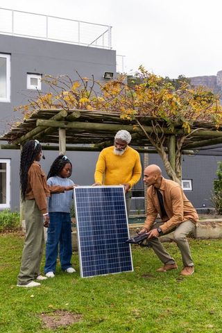 Multigenerational african american family learning solar panel installation in backyard