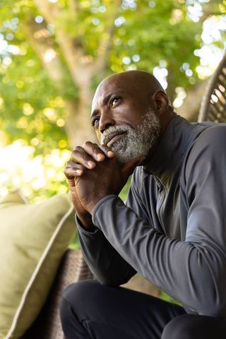 Mature african man sitting on porch chair contemplating life with calm reflective expression