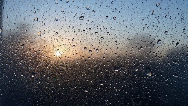 Sunrise refracting through raindrops on window glass, moody condensation dawn