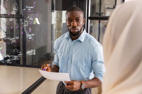 Business Professional Presenting Ideas on Transparent Board